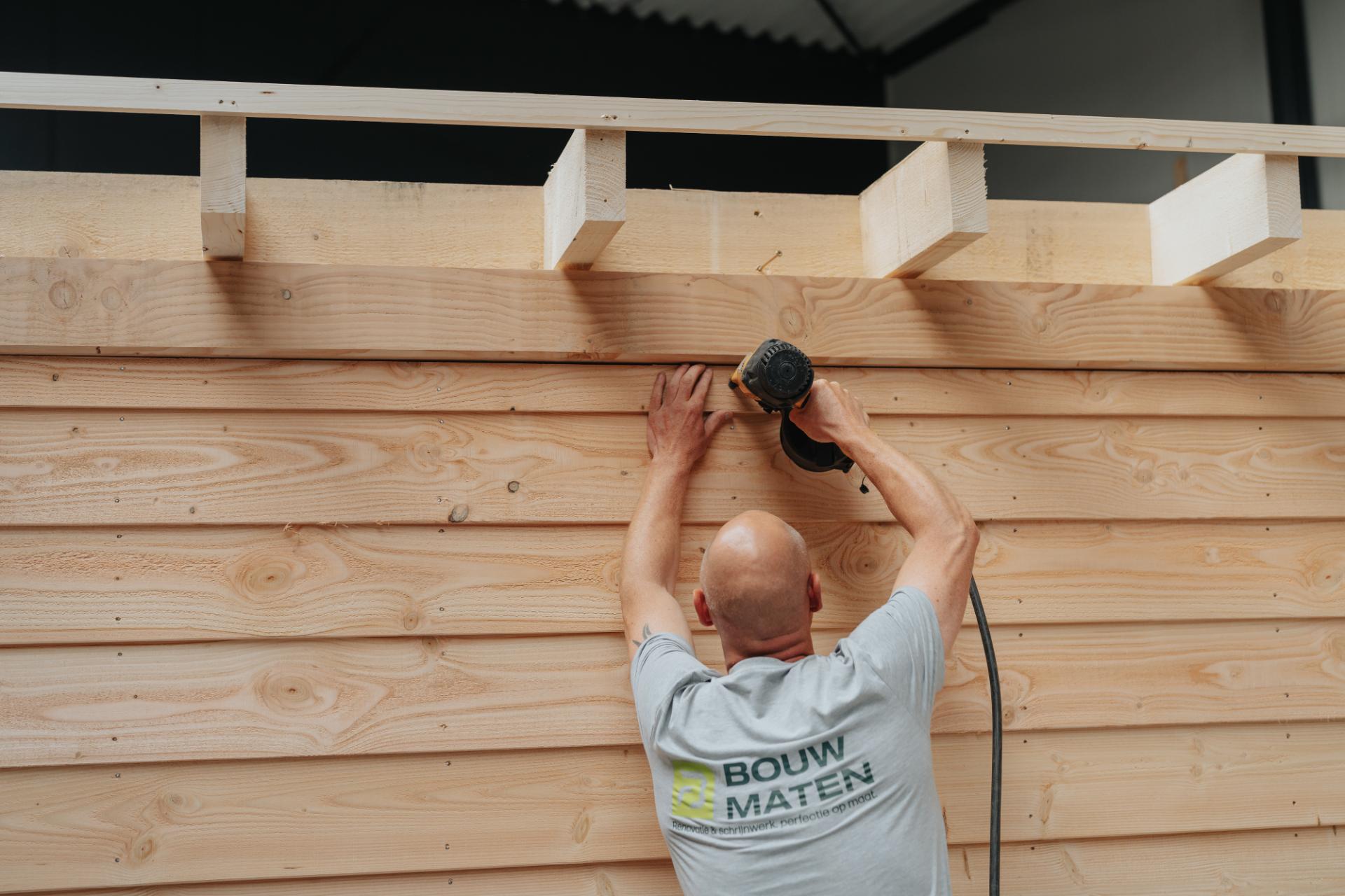 Schrijnwerker werkt een houten bijgebouw nauwkeurig af