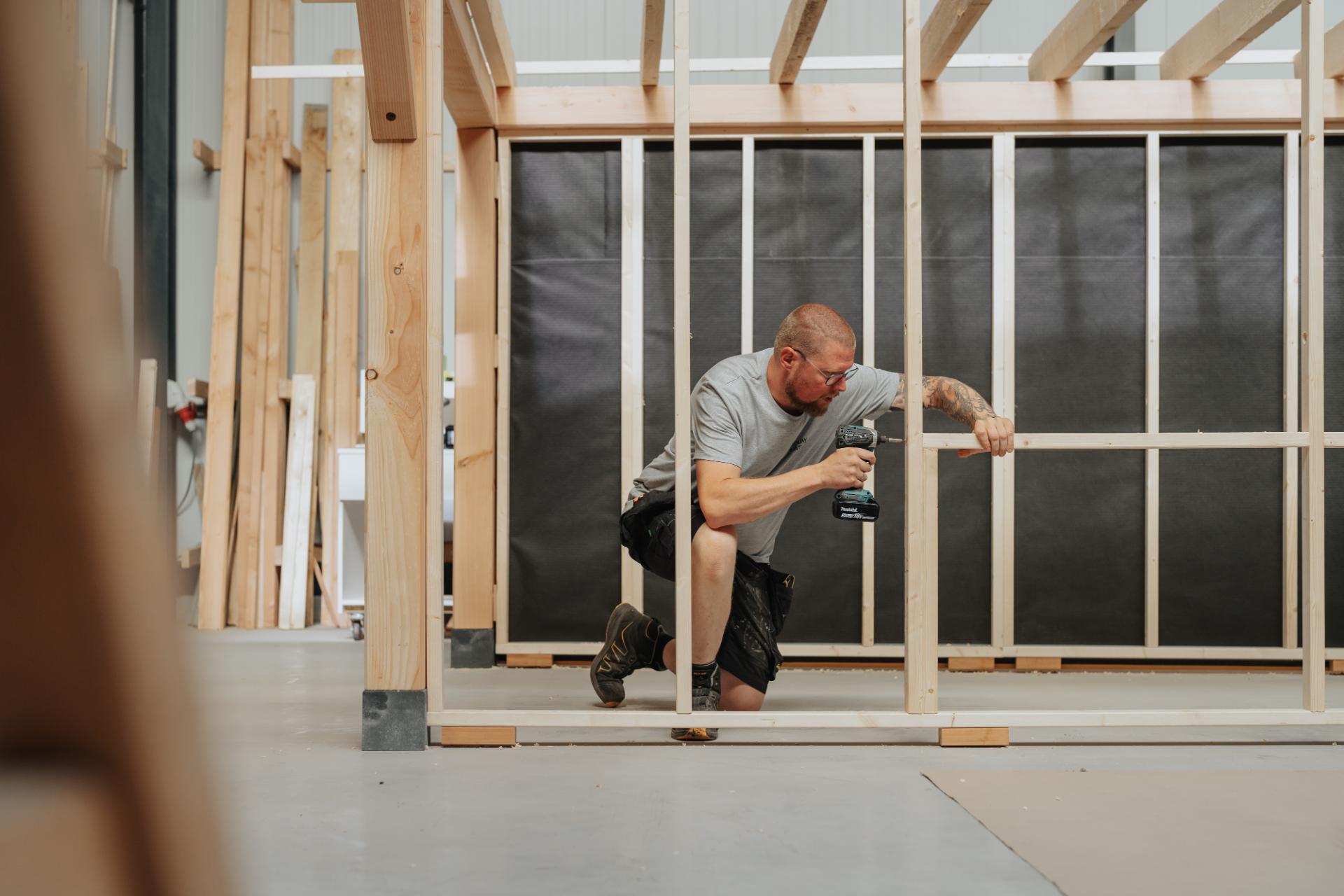 Schrijnwerker plaatst binnenwanden in een houten constructie