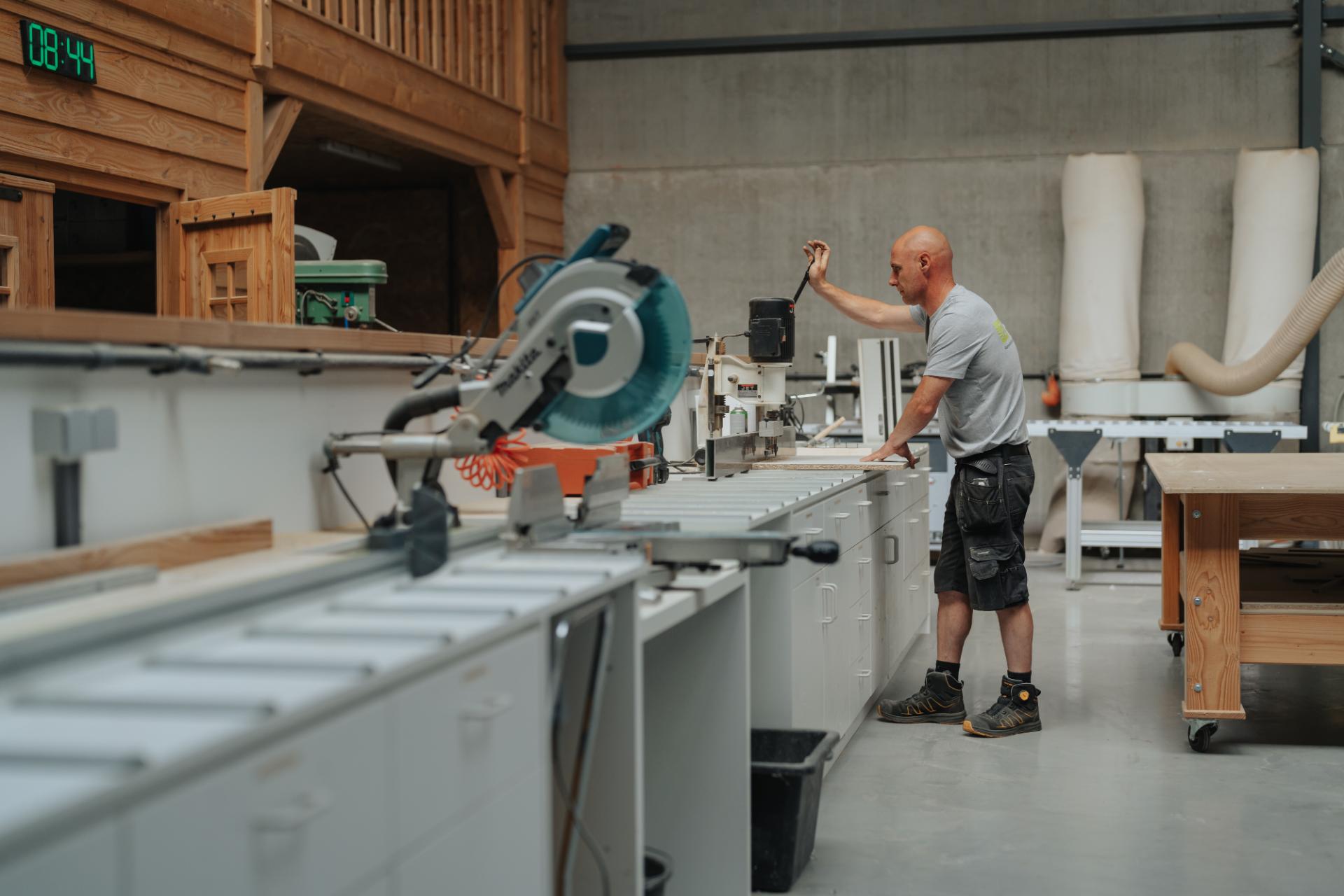 Schrijnwerker werkt houten balken af met een houtbewerkingsmachine