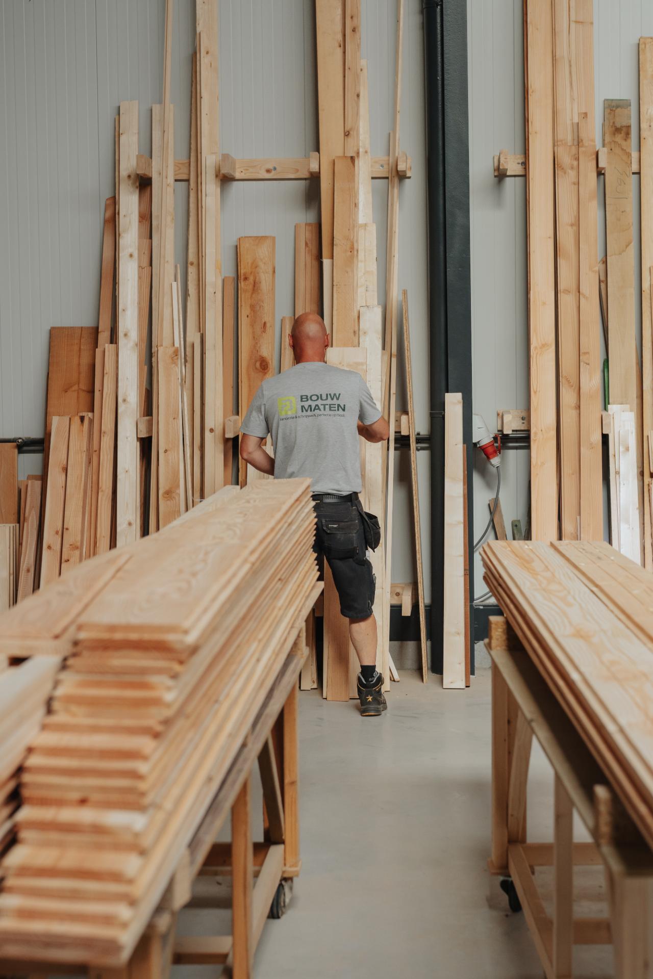 	Vakman verplaatst een houten wandpaneel voor een maatwerk project