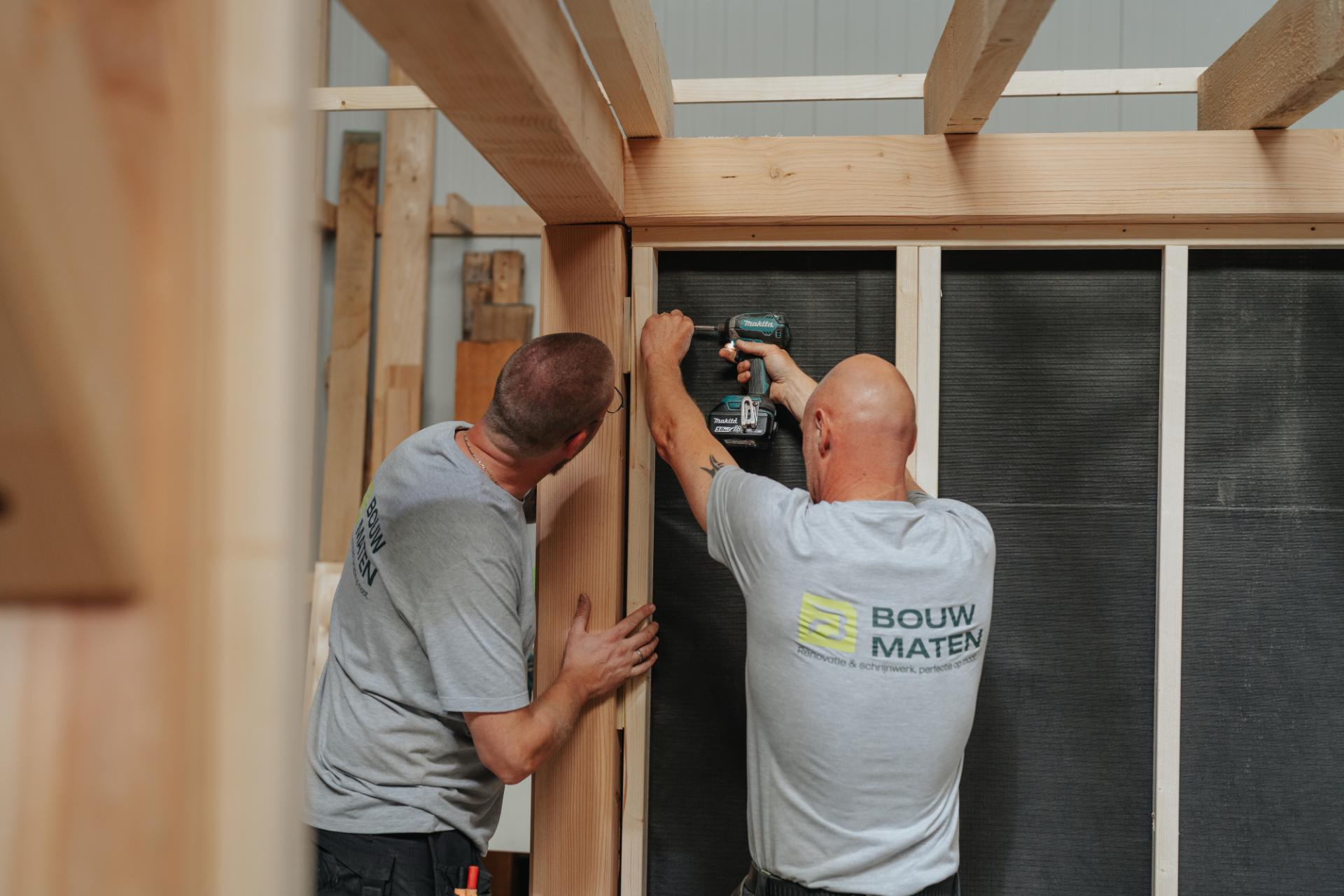 Vakmannen van BouwMaten monteren een prefab houtskeletbouw wand in het atelier.	