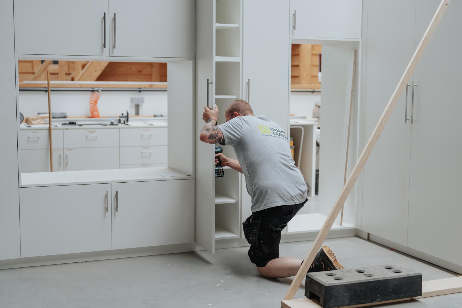 Schrijnwerker monteert een maatwerkkast in de werkplaats van Bouwmaten