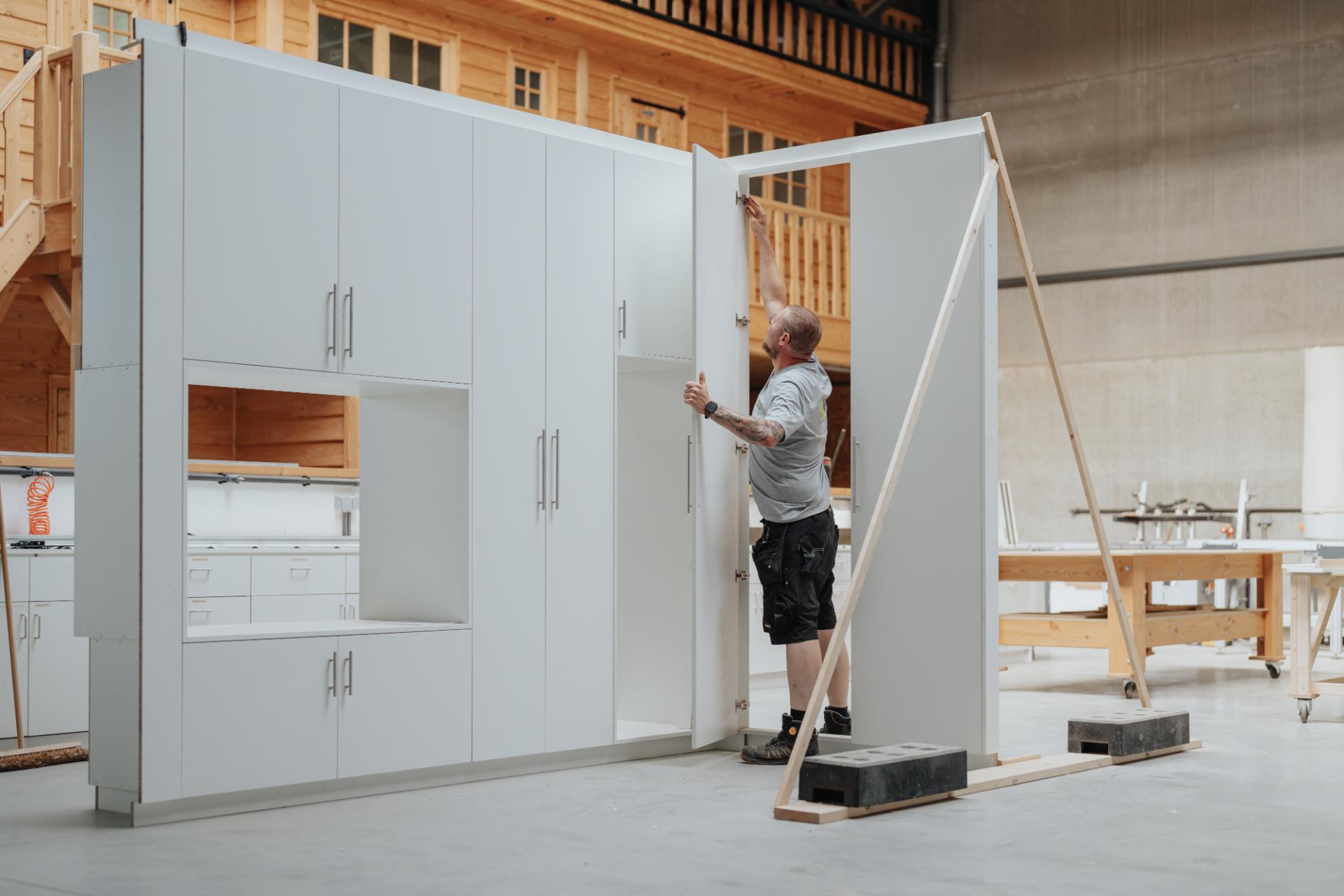 Schrijnwerker plaatst een maatwerk kastenwand in de werkplaats
